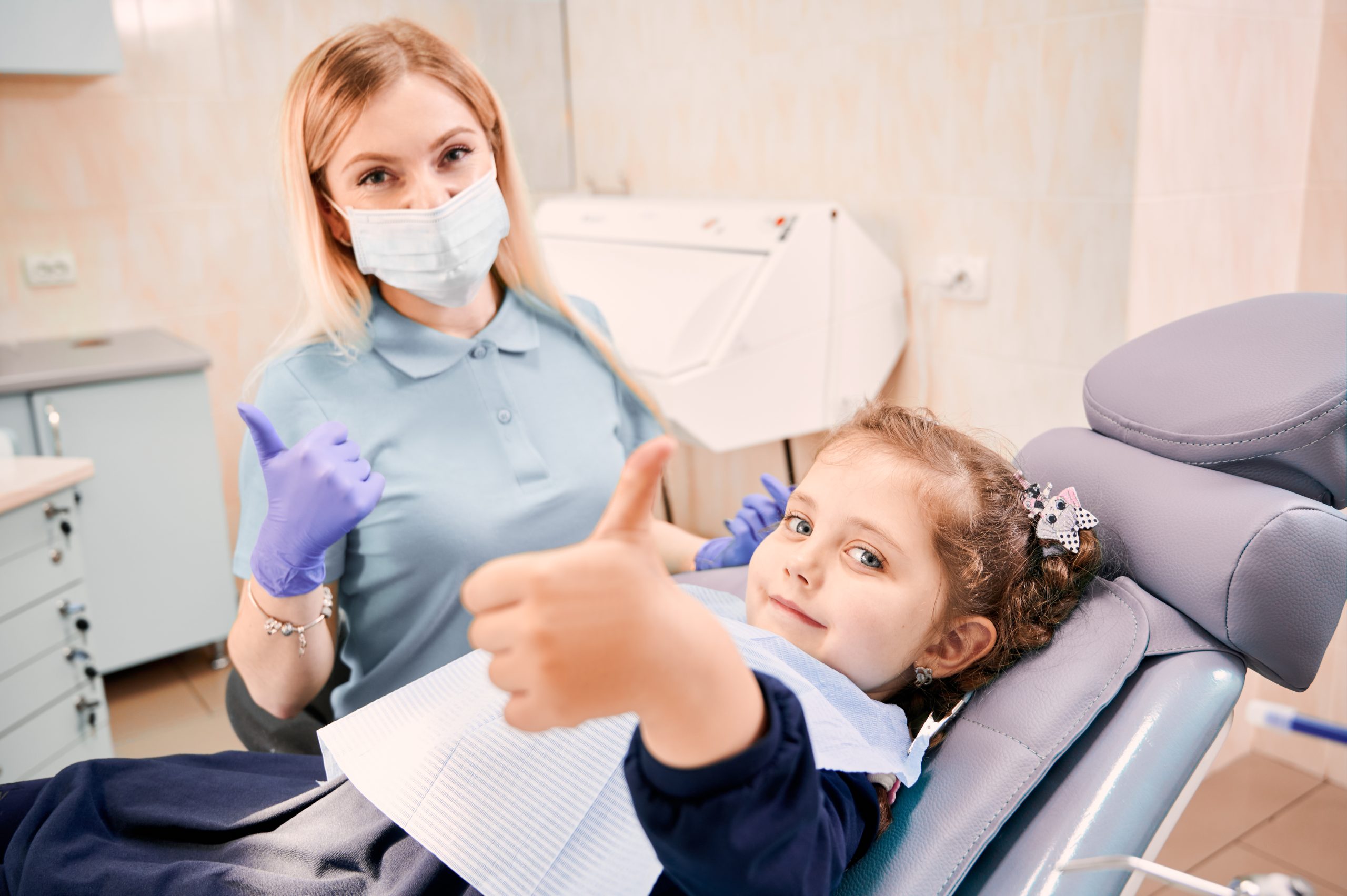 female dentist cute little girl giving thumbs up scaled